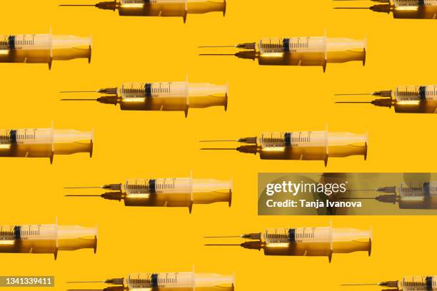 pattern of syringes with a vaccine on yellow background. concept of medical treatment or vaccination. - botoxinjektion bildbanksfoton och bilder