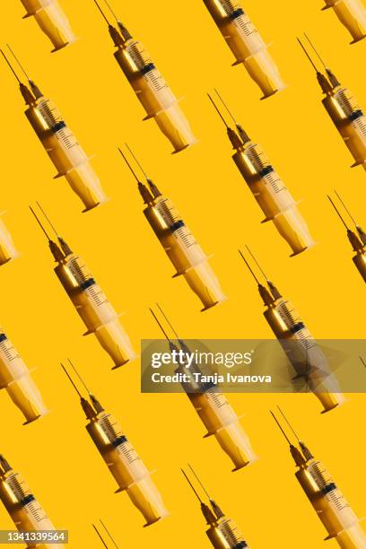 pattern of syringes with a vaccine on yellow background. concept of medical treatment or vaccination. - plastische chirurgie stockfoto's en -beelden