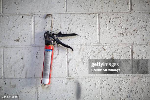 caulking gun hanging on the white stone wall - glue gun stock pictures, royalty-free photos & images