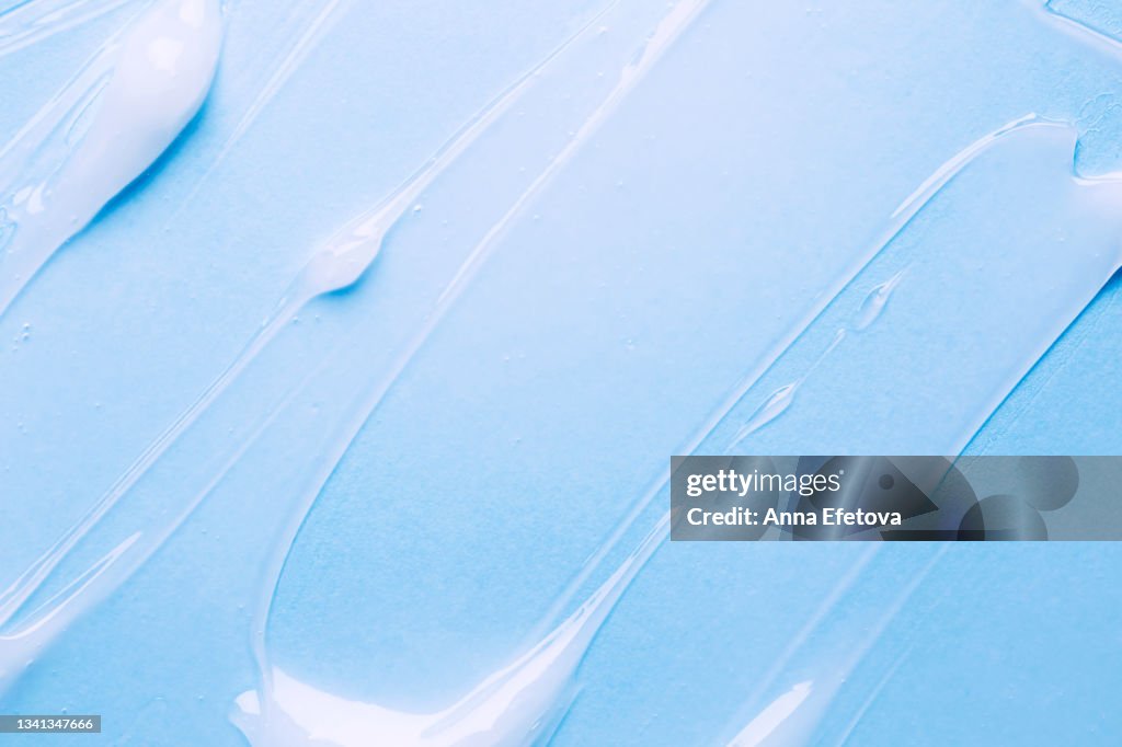 Texture of transparent gel for body care on blue background. Flat lay style