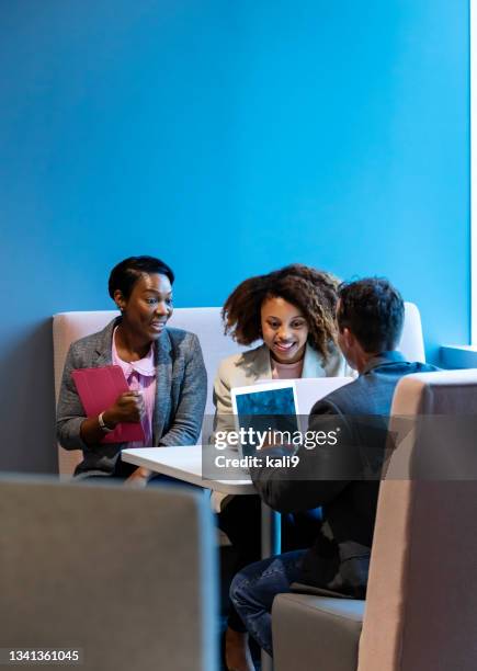 three multiracial workers meeting, using laptops - laptop coloured background stock pictures, royalty-free photos & images