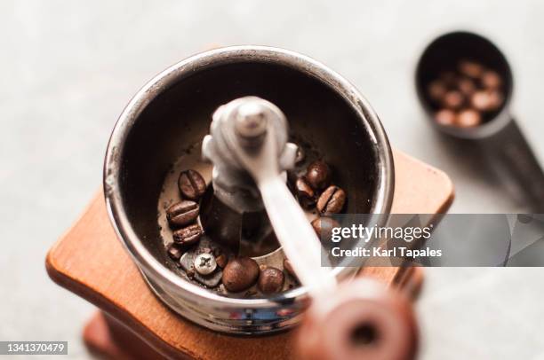 a southeast asian man is grinding coffee beans on a manual coffee grinder - 挽く ストックフォトと画像