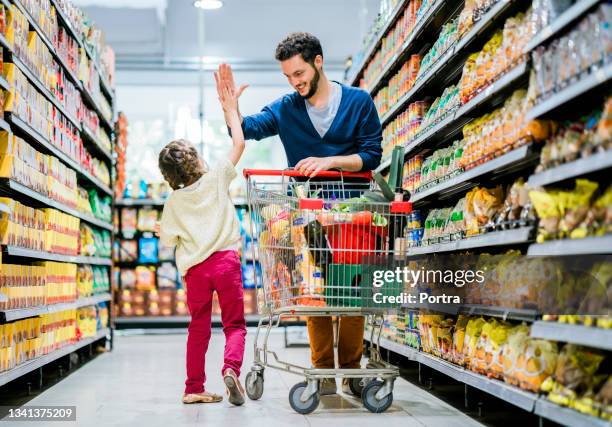 man giving high five to daughter while shopping - happy smiling people multi generations stock pictures, royalty-free photos & images