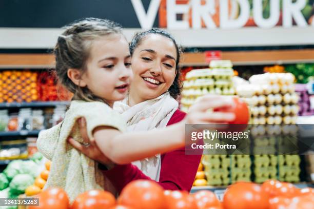 mother and daughter buying groceries at store - buying groceries stock pictures, royalty-free photos & images
