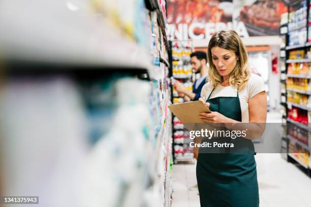 reife besitzerin, die im supermarkt arbeitet - aushilfsverkäufer stock-fotos und bilder