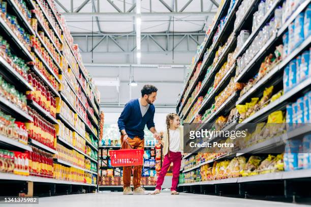 daughter buying groceries with father in store - grocery aisles stock pictures, royalty-free photos & images