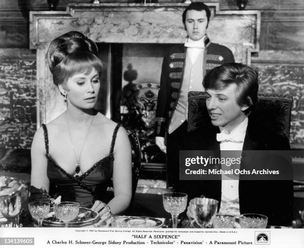 Penelope Horner and Tommy Steele sitting at the dining table together in a scene from the film 'Half A Sixpence', 1967.