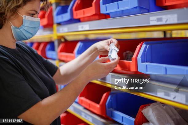 warehouse worker holding an item from storage trays in a row on racks - filing tray stock pictures, royalty-free photos & images