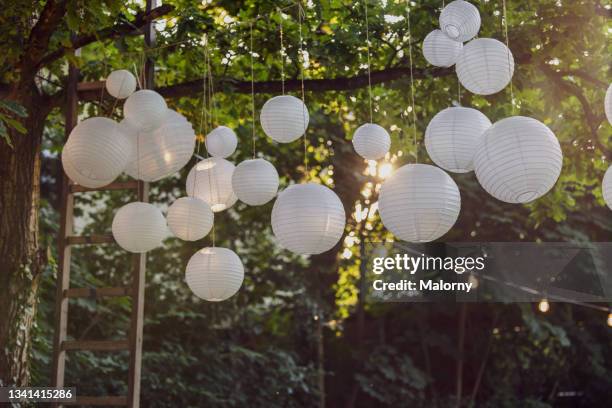 white paper lanterns hanging in trees in the garden. decoration service. garden party, summer festival, wedding. - hanging in garden photos et images de collection