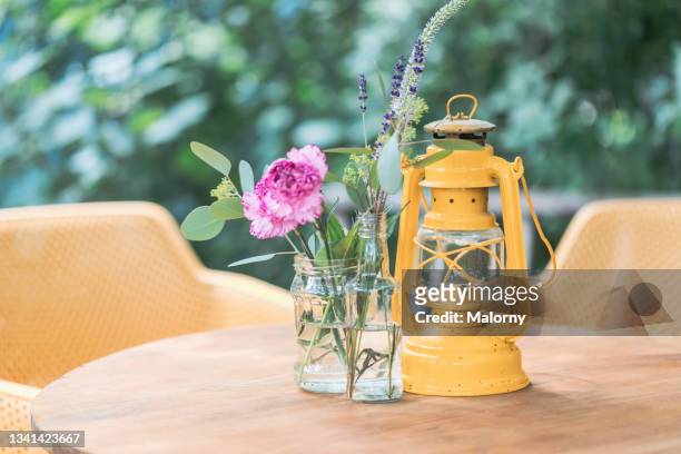 close-up of flowers in a glass vase and a yellow lantern. decoration service. garden party, summer festival, wedding. catering. - close up of flower bouquet stock-fotos und bilder