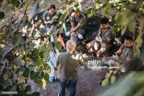 group of volunteers sitting in circle and having a meeting to make a plan about cleaning the area from garbage - nature resources and conservation agency stock pictures, royalty-free photos & images