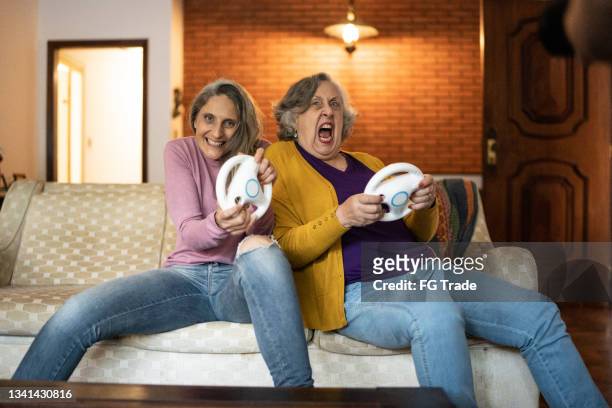 fille et mère jouant à des jeux vidéo à la maison - pov - mamie grimace photos et images de collection