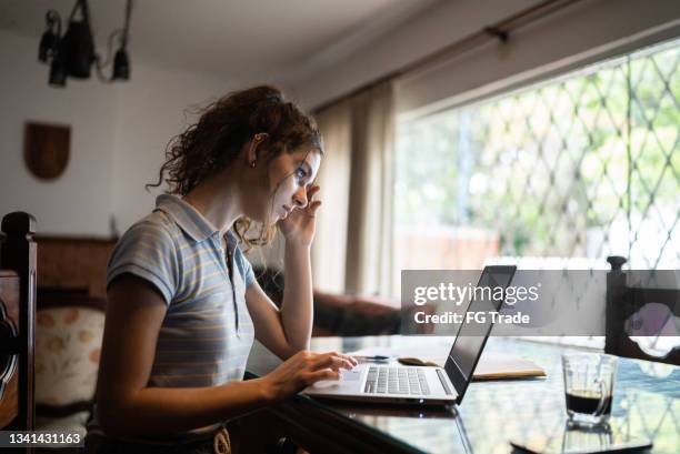 giovane donna che digita sul laptop a casa - complaining foto e immagini stock