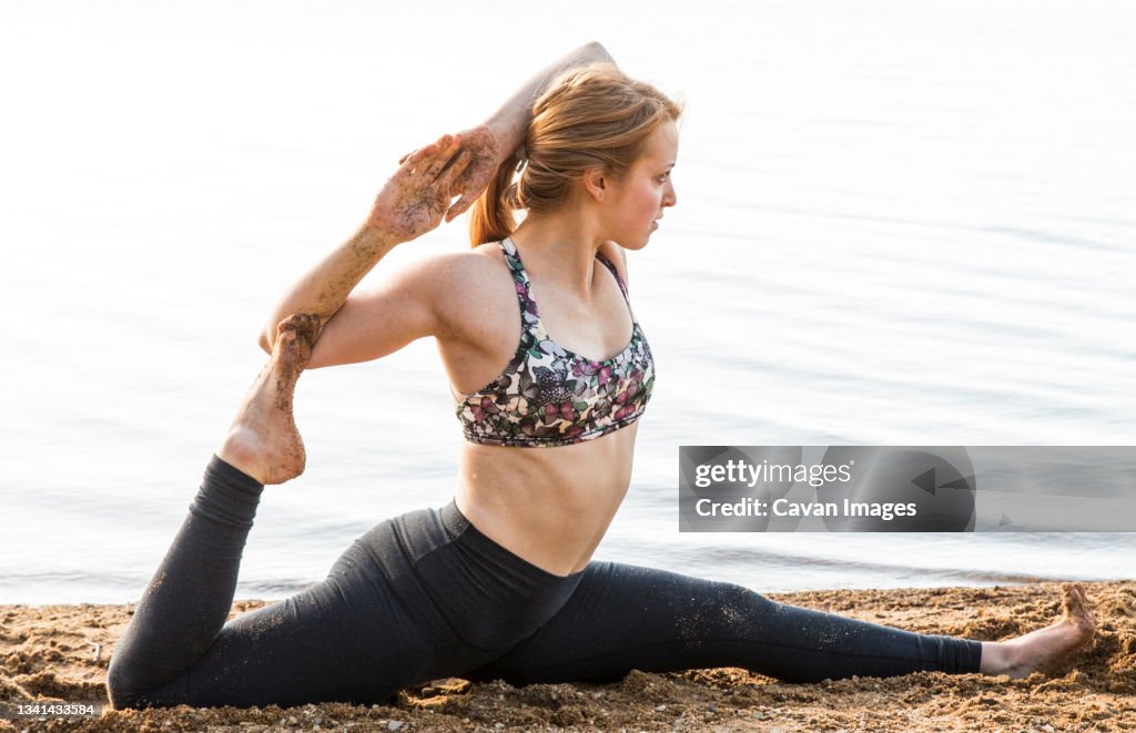 Female yogi in advanced split on the sand