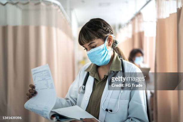 healthcare female worker reading medical record at hospital - medical research paper stock pictures, royalty-free photos & images