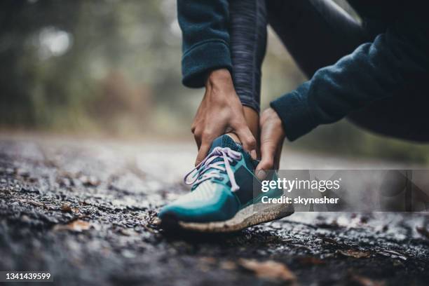 close up of unrecognizable athlete holding her ankle in pain at the park. - distenção imagens e fotografias de stock