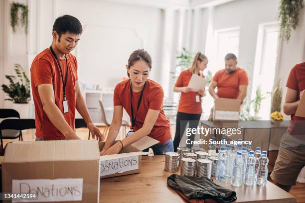 team of volunteers  in the donation center sharing and packing food,clothes,water in boxes for the people in need - distribution center stockfoto's en -beelden