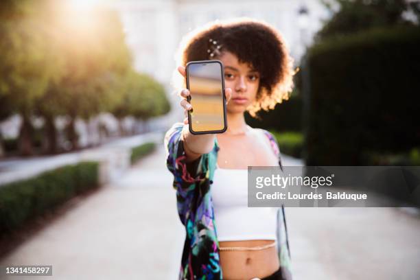 teenager teaches mobile phone screen to camera - mostrare foto e immagini stock