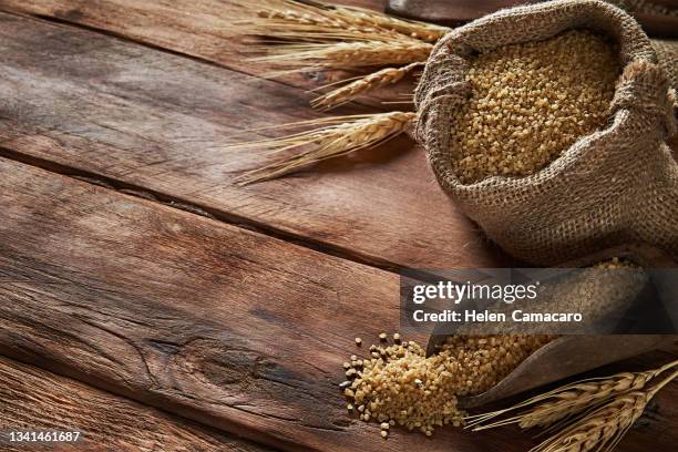 uncooked wheat grain in burlap sack on rustic wooden table - cereales stock pictures, royalty-free photos & images