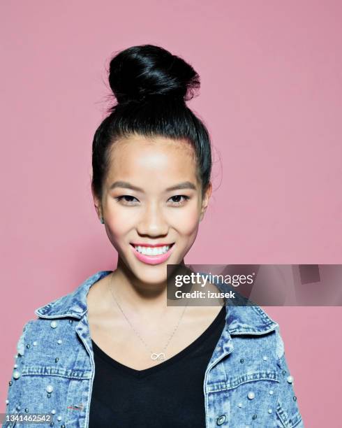 smiling young woman against pink background - hair bun stockfoto's en -beelden