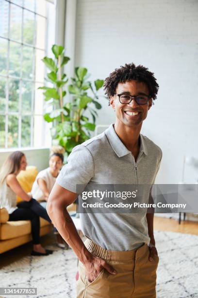 young male designer smiling while standing in a modern office - incidental people stock pictures, royalty-free photos & images