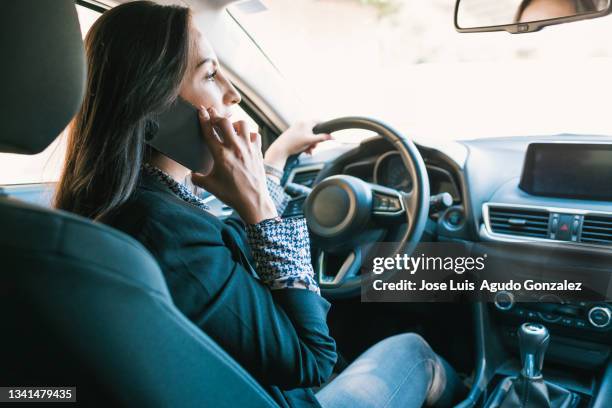 woman speaking on smartphone in car - steering wheel stockfoto's en -beelden