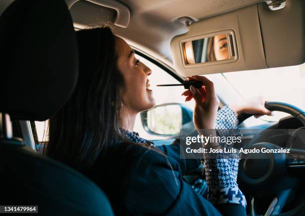 woman applying makeup in car - cosmetic stockfoto's en -beelden