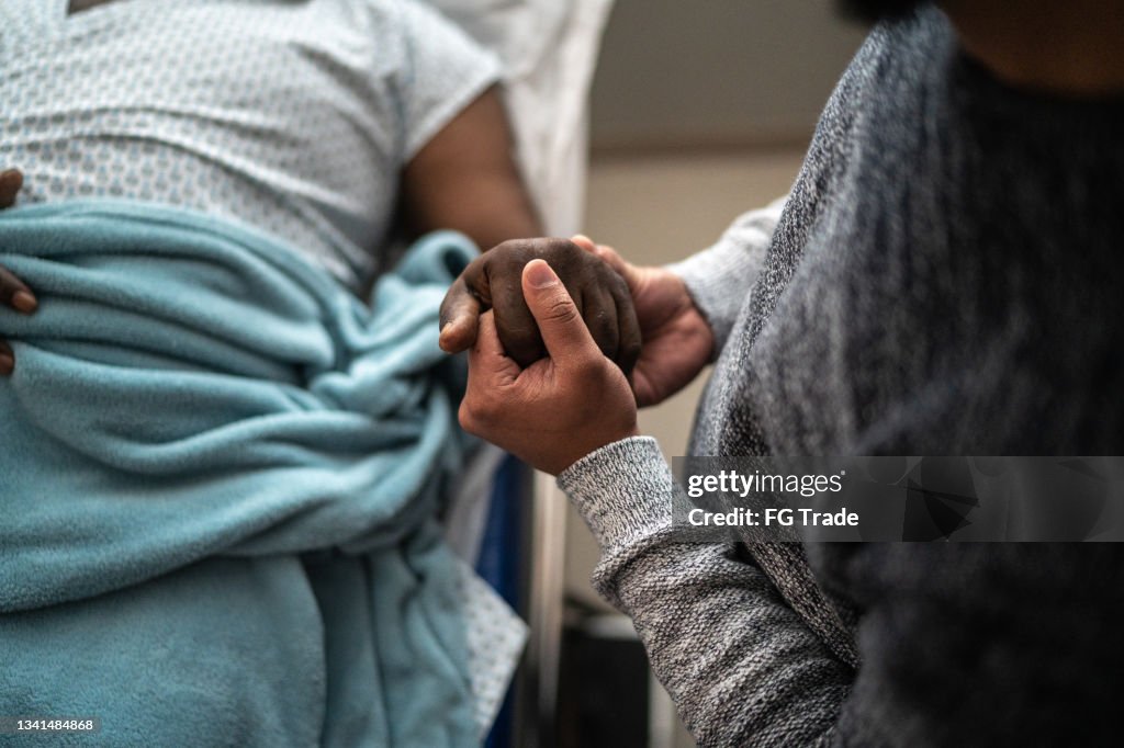 Sohn hält Vaters Hand im Krankenhaus