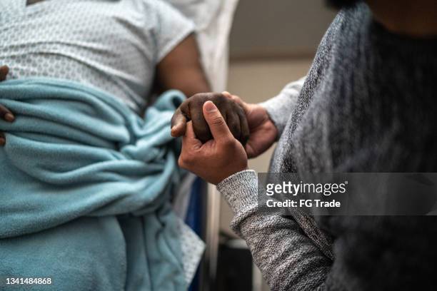 sohn hält vaters hand im krankenhaus - spirituality stock-fotos und bilder