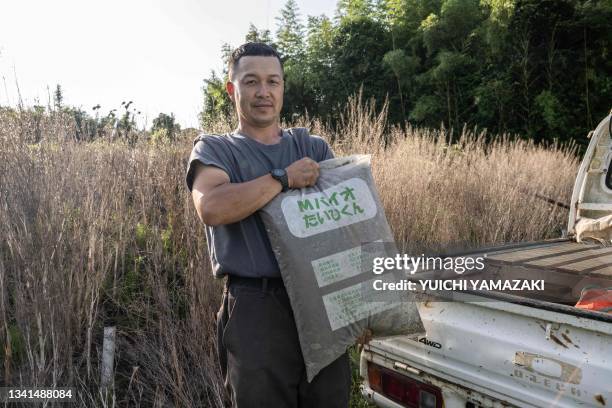 This picture taken on June 13, 2023 shows Nobuyoshi Fujiwara, an owner of lettuce farm, posing for photographs with a bag of human faeces-made...