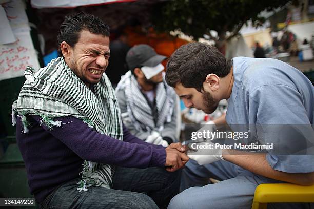 Man reacts as a medic stitches a wound at a make shift first aid post in Tahrir Square on November 27, 2011 in Cairo, Egypt Protestors are continuing...