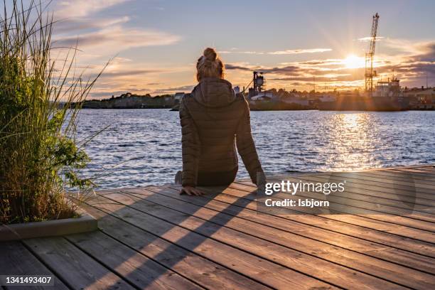 rear view of woman sitting on a pier - oslo city life stock pictures, royalty-free photos & images