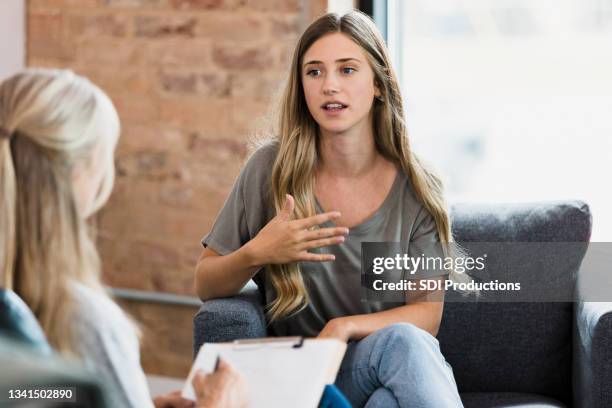 gesten der weiblichen klientin im gespräch mit einem nicht erkennbaren therapeuten - psychiatrie und psychotherapie stock-fotos und bilder