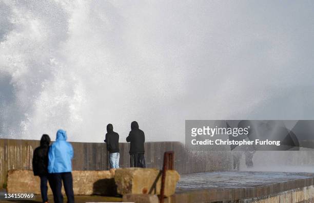 People watch waves crash over the Holyhead breakwater as the search continues for the crew of cargo vessel The Swanland which sank off north Wales on...