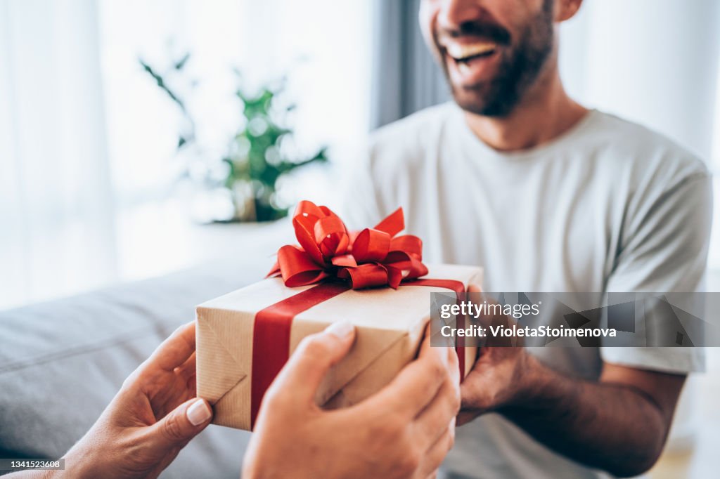 Cheerful young man receiving a gift from his girlfriend.