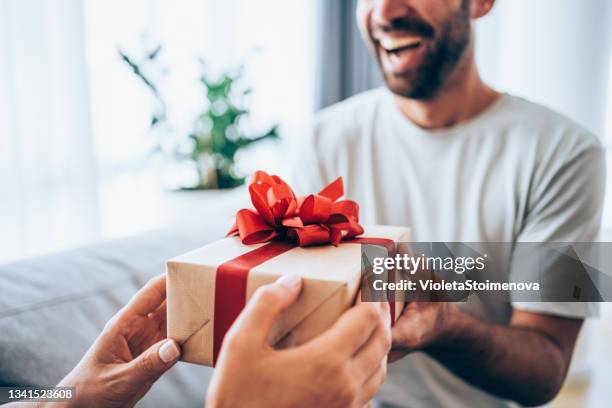 cheerful young man receiving a gift from his girlfriend. - passing giving 個照片及圖片檔