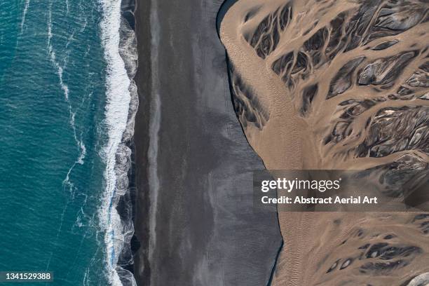 ocean waves, black sand beach and a braided river photographed by drone from directly above, iceland - tide rivers stock pictures, royalty-free photos & images