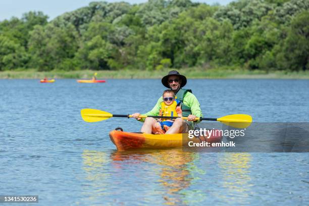 father & son kayaking on lake in summer - family red canoe stock pictures, royalty-free photos & images
