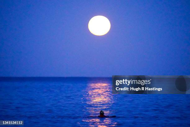 Lone swimmer takes to the sea to swim under the Harvest Moon on September 20, 2021 in Swanpool Beach, Falmouth, England.