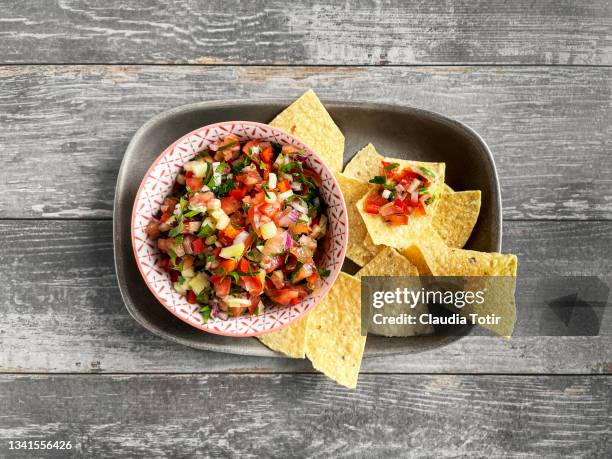 bowl of salsa with corn chips on gray, wooden background - hot sauce stock pictures, royalty-free photos & images