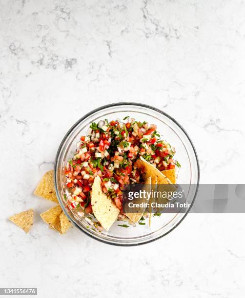 home made salsa with corn chips in a bowl on white, marble background - coriandre fond blanc photos et images de collection