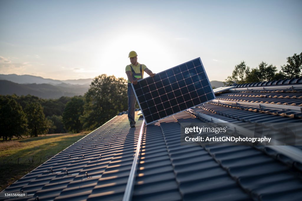 Arbeiter, die Sonnenkollektoren auf ein Dach stellen