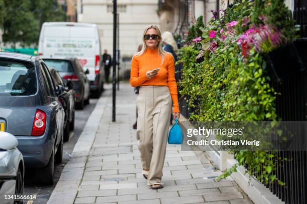 Guest is seen wearing orange jumper, beige pants, blue bag outside Paul & Joe during London Fashion Week September 2021 on September 20, 2021 in...