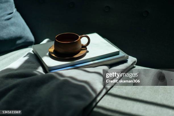 wooden cup of coffee and books on the cozy sofa - book table stockfoto's en -beelden