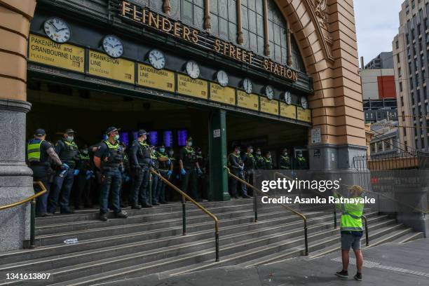 Police are seen at the front of Flinders Street station as thousands march through Melbourne after State Government announces construction shutdown...