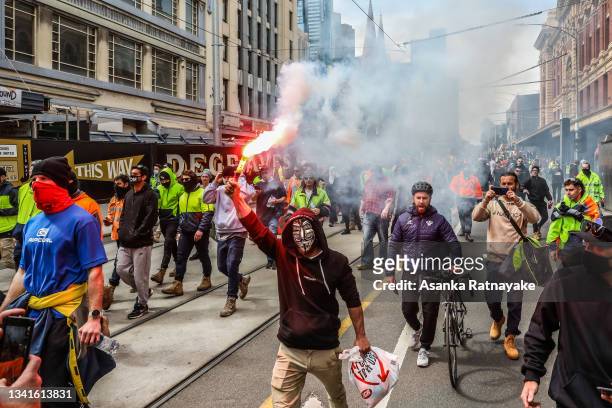 Protestors are seen marching as a flare is lit as thousands march through Melbourne after State Government announces construction shutdown on...