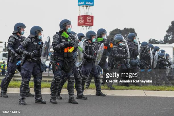 Riot police are seen on guard at the bottom of Westgate Bridge as thousands march through Melbourne after State Government announces construction...