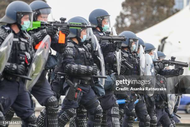 Riot police are seen on guard at the bottom of Westgate Bridge as thousands march through Melbourne after State Government announces construction...