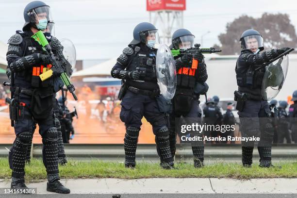 Riot police officer is seen pointing his gun as thousands march through Melbourne after State Government announces construction shutdown on September...