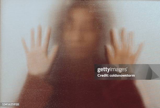 opfer häuslichen missbrauchs mit gegen glasfenster gedrückten händen - angriff stock-fotos und bilder
